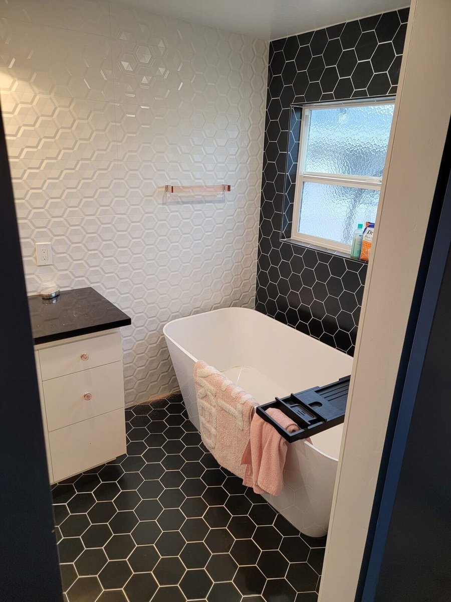 Modern bathroom remodel with a white freestanding tub, black hexagon tile floors, and geometric wall tiles by H&H Builds in Sacramento, CA