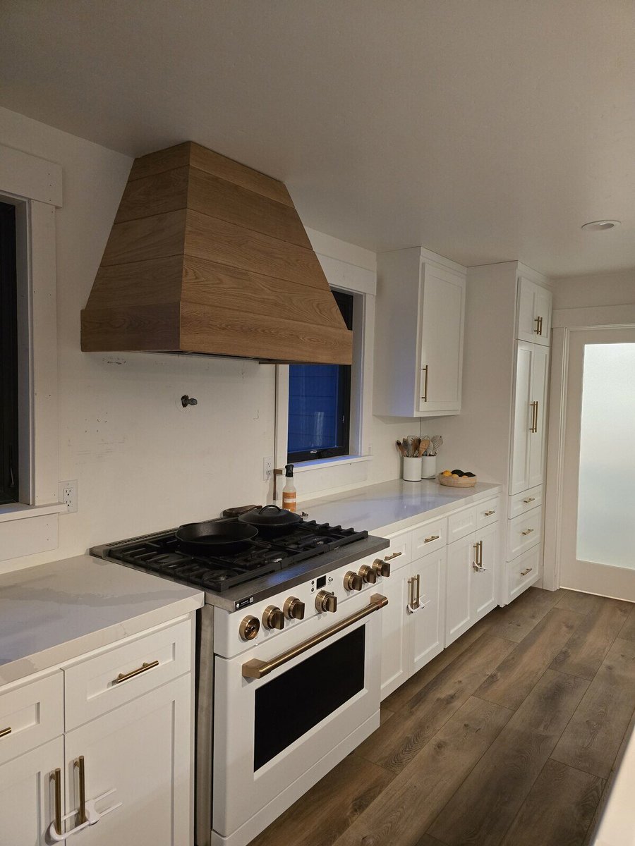 Modern kitchen remodel featuring white cabinetry, gold hardware, and a custom wooden range hood in Sacramento, CA, by H&H Builds