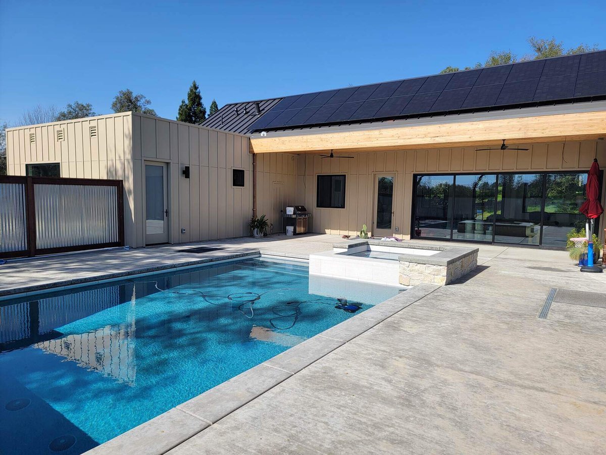 Outdoor remodel featuring a swimming pool, spa, and modern patio area with solar-paneled roofing by H&H Builds in Sacramento, CA