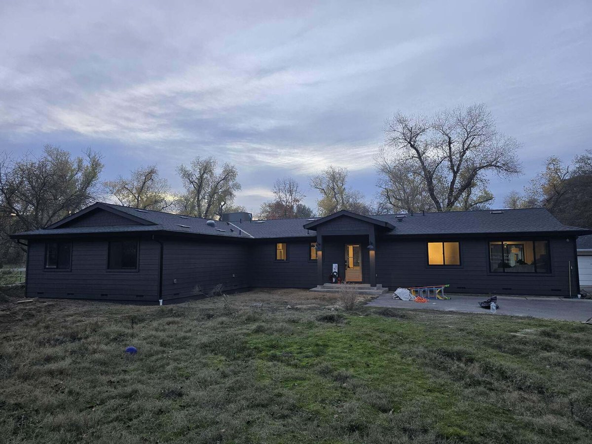 Wide shot of a modern black home remodel featuring large windows and spacious landscaping in Sacramento, CA, by H&H Builds